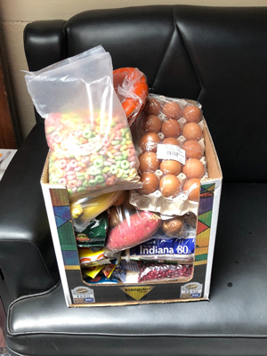 Picture of a box full of food.Eggs,cereal, powered milk, rice, beans, oil, sugar, coffee, meat,noodles, tomatosauce, tortilla mix, friut, vegetables and more.